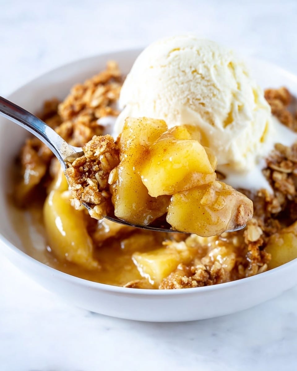 A glass baking dish holds a three-layer dessert with a crumbly, golden-brown topping that looks crunchy and textured. The top layer is thick with small oats and crumbs, spread evenly over a middle layer of soft, yellow apple slices that are visible where a piece has been cut out. Below the apples, a shiny caramel sauce pools slightly at the bottom, showing a sticky texture. In the background, a yellow apple (whole and sliced) sits on a white marbled surface. Photo taken with an iphone --ar 4:5 --v 7