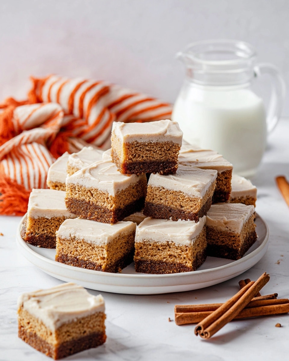 Stacked square cake slices are arranged on a white round plate placed on a white marbled surface. Each slice has two layers: a thick bottom layer of dark brown cake with a moist, crumbly texture, and a top layer of smooth, light beige frosting. Some slices are scattered around the plate on the white marbled surface. To the right, three cinnamon sticks rest beside the plate. In the background, a transparent glass pitcher filled with milk sits near a crumpled orange and white striped cloth. The photo is taken with an iphone --ar 4:5 --v 7