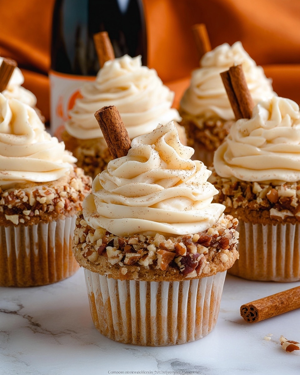 The image shows several cupcakes with three visible layers: the bottom layer is a golden-brown cupcake with a smooth texture, the middle layer is a thick white frosting covered with chopped nuts around the sides, and the top layer is a swirl of creamy white frosting that rises high in soft peaks. Each cupcake has a cinnamon stick inserted vertically on one side. The cupcakes are set closely together on a folded burnt orange cloth, with a background of white marbled texture. Photo taken with an iphone --ar 4:5 --v 7