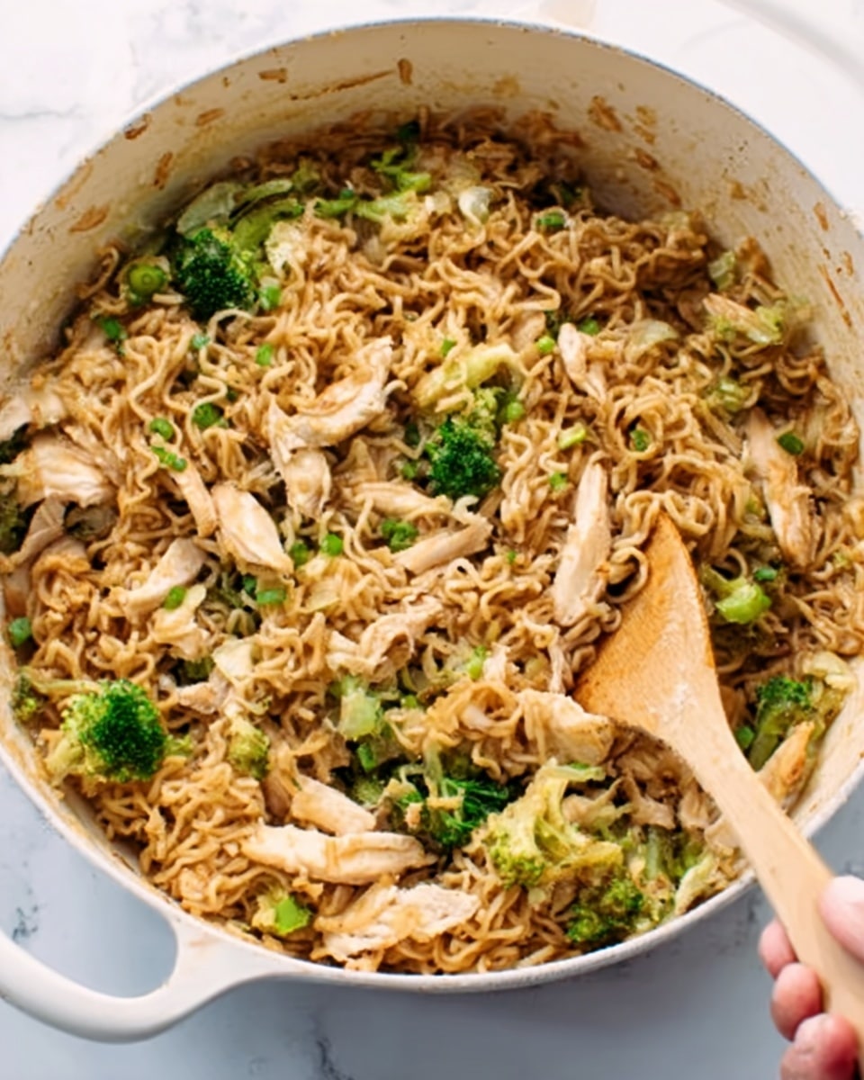 The image shows a close-up of cooked brown noodles mixed with small pieces of green broccoli and shredded beige chicken in a large white pot with blue handles. A wooden spoon is stirring the food, with a woman's hand holding the spoon from the right side, the spoon moving through the noodles and vegetables. The brown noodles have a slightly glossy texture, while the broccoli adds a fresh green color. The chicken pieces are scattered evenly throughout the noodles, adding light tones to the dish. The background features a white marbled texture. Photo taken with an iphone --ar 4:5 --v 7