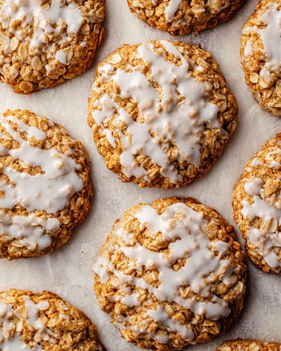 The image shows several round oatmeal cookies spread out on a flat surface with a white marbled texture. Each cookie has one layer: a golden-brown base that looks soft and chewy with visible oats and small cracks on the surface, topped with a thin, uneven layer of glossy white icing that is slightly dripping off the edges in some places. The cookies are arranged close to each other, showing different sizes of icing patches across the tops, that vary from light to thicker coverage creating a contrast with the rough oatmeal texture beneath. Photo taken with an iphone --ar 4:5 --v 7