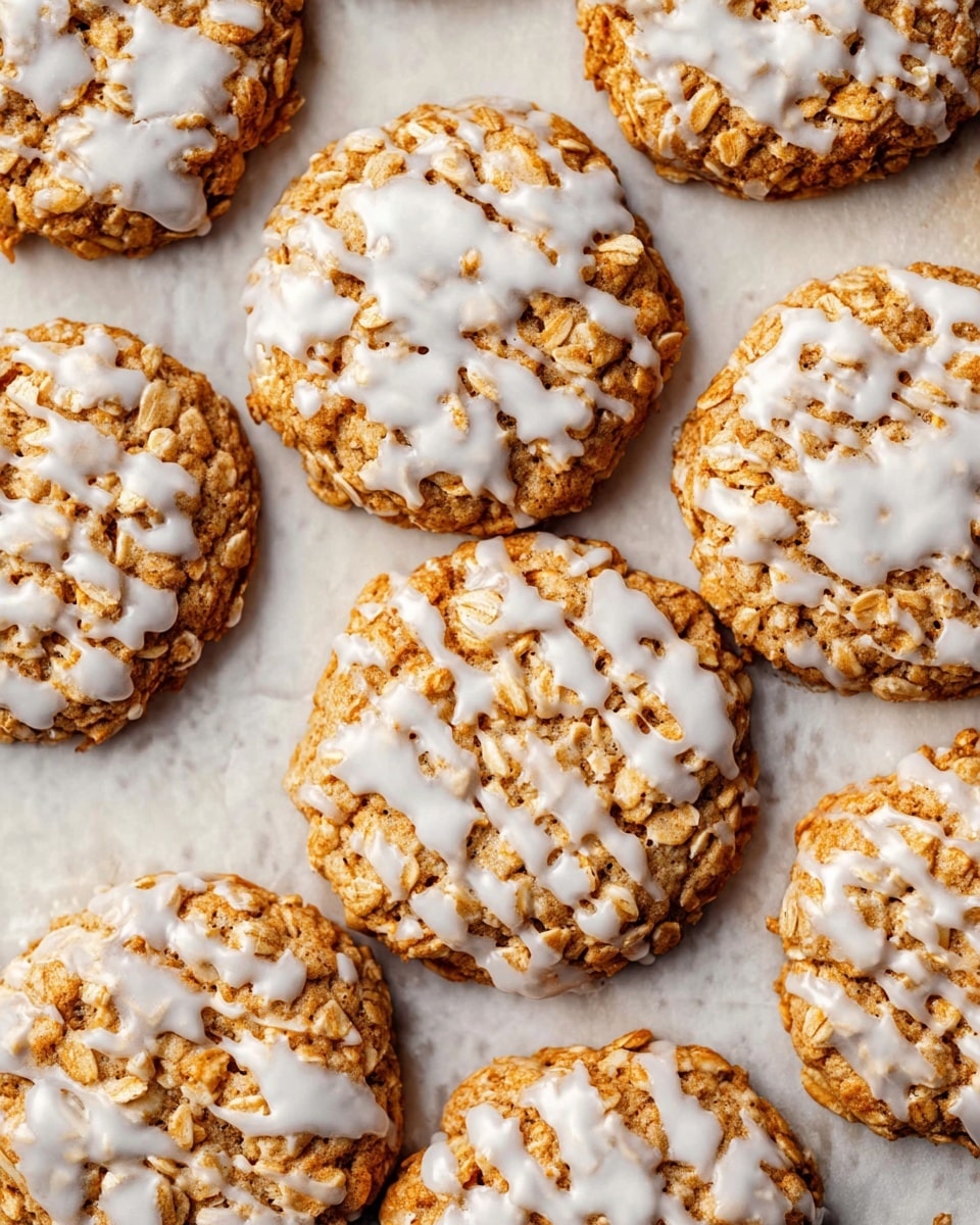 The image shows a close-up of several oatmeal cookies with white icing drizzled unevenly over the top. Each cookie is round with a rough, textured surface from the oats, with the icing forming irregular patches that contrast with the golden-brown color of the cookies. The cookies are arranged closely together on a light parchment paper, which lies on a white marbled texture background. The overall look is rustic and homemade, with some icing slightly spilling off the edges of a few cookies. photo taken with an iphone --ar 4:5 --v 7