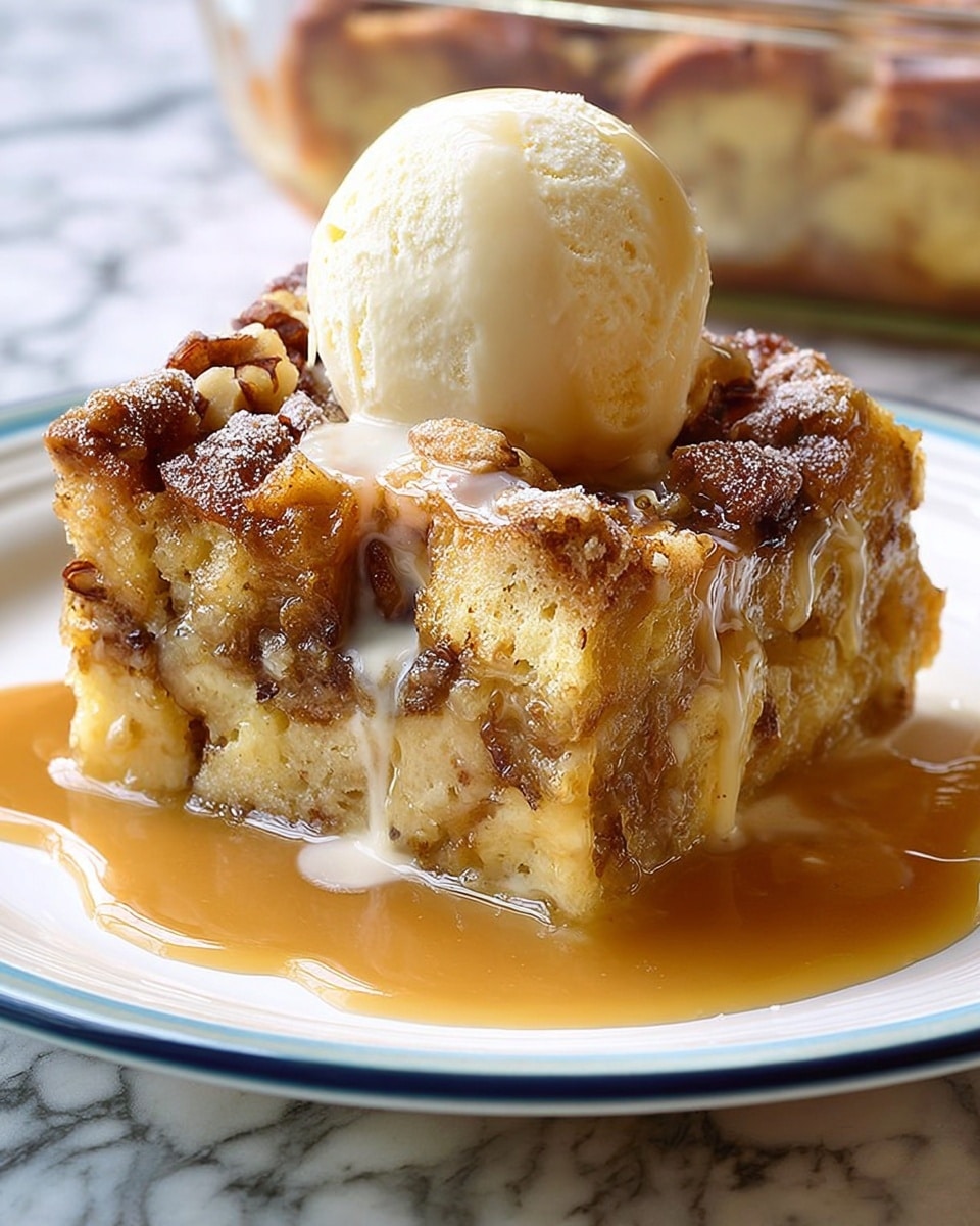A thick square piece of bread pudding with visible chunks of bread and nuts, layered richly with a golden brown cinnamon topping that looks crunchy and slightly caramelized. The pudding is soaked in a smooth, light brown sauce that drips down the sides and pools on a white plate with a thin blue rim. A round, creamy white scoop of ice cream sits on top, slightly melting into the warm pudding. The background shows a blurry glass baking dish and the surface is a white marbled texture. photo taken with an iphone --ar 4:5 --v 7