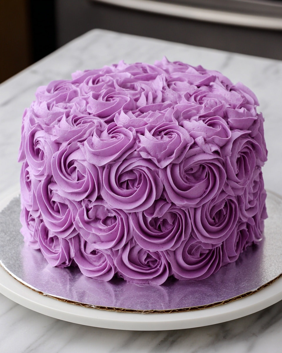 A round cake with a smooth, even layer of lavender-purple frosting on top and around the sides is placed on a white cake stand with a marbled white surface beneath. The woman’s hand is holding the cake stand steady while another woman’s hand pipes large, thick rosettes of the same lavender frosting around the bottom half of the cake, forming two neat rows of swirl shapes with detailed ridges. The frosting looks creamy and soft, and the cake is sitting on a white cake board above the stand. Photo taken with an iphone --ar 4:5 --v 7
