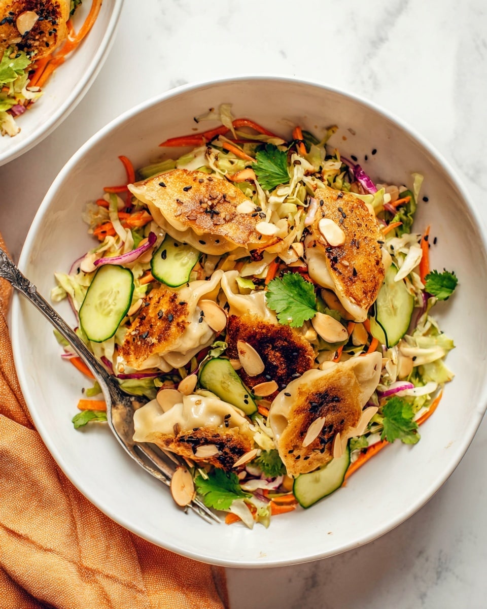 A white bowl holds a colorful salad with four warm, golden-brown pan-fried dumplings on top. The dish has a base layer of thinly shredded cabbage and carrots mixed with thinly sliced red onions, giving it a mix of pale green, bright orange, and purple colors. Scattered on top are thick slices of bright green cucumber and toasted almond slices, contrasting in texture and color. Small dark sesame seeds and fresh cilantro leaves are sprinkled over the entire salad, adding spots of black and green. A silver fork rests inside the bowl on the left side. The bowl sits on a white marbled surface with a light orange cloth nearby. Photo taken with an iphone --ar 4:5 --v 7